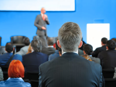 man watching speaker at event - how to plan a corporate event