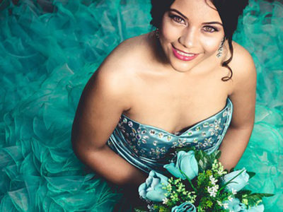Happy Hispanic Or Latina Girl Wearing A Quinceanera Dress And Holding Flowers At Quinceanera Venue